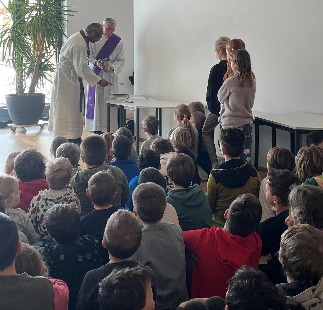 Aschermittwoch in der Volksschule Vorderthiersee: Pfarrer Harrison Markose und Diakon Toni Pirchmoser starteten mit den Schülerinnen und Schülern in die Fastenzeit.