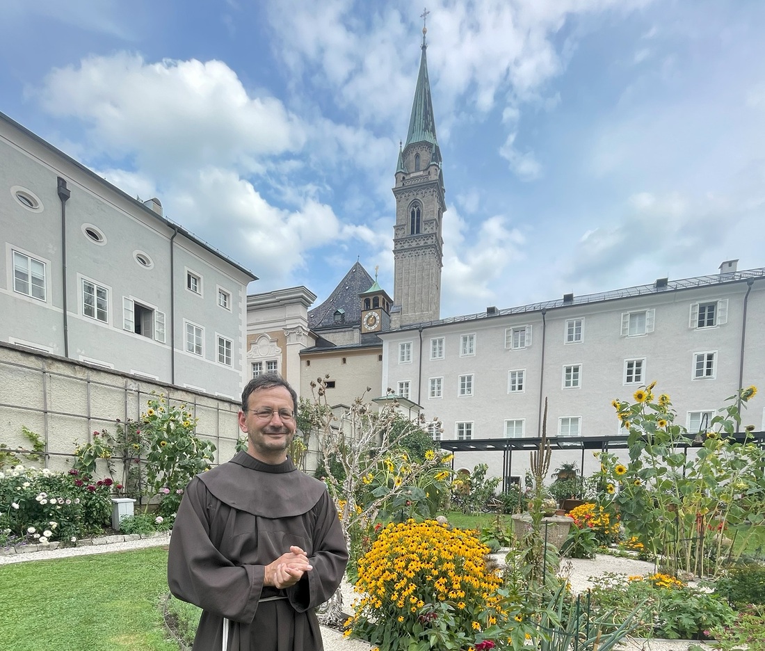 P. Moritz Windegger mit Blick vom Klostergarten auf die Franziskanerkirche.