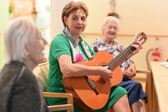 Die Salzburgerin Christine Exner, wie man sie im Seniorenwohnhaus Nonntal kennt und schätzt – mit der Gitarre begleitet sie eine Gesangsrunde.