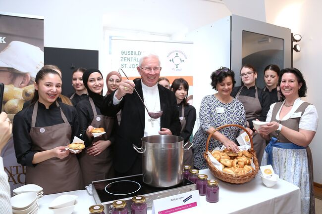 Erzbischof Franz Lackner, kfb-Salzburg-Vorsitzende Michaela Luckmann und kfb-Salzburg-Leiterin Renate Orth-Haberler mit Schülerinnen des Ausbildungszentrums St. Josef beim Benefizsuppenessen im Salzburger Kapitelsaal.