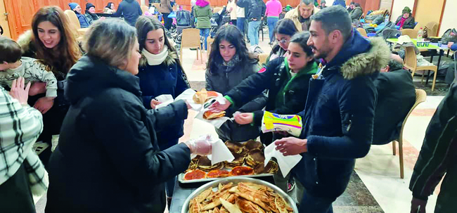 Freiwillige verteilen in der Suppenküche der Pfarre St. Francis in Aleppo Essen.