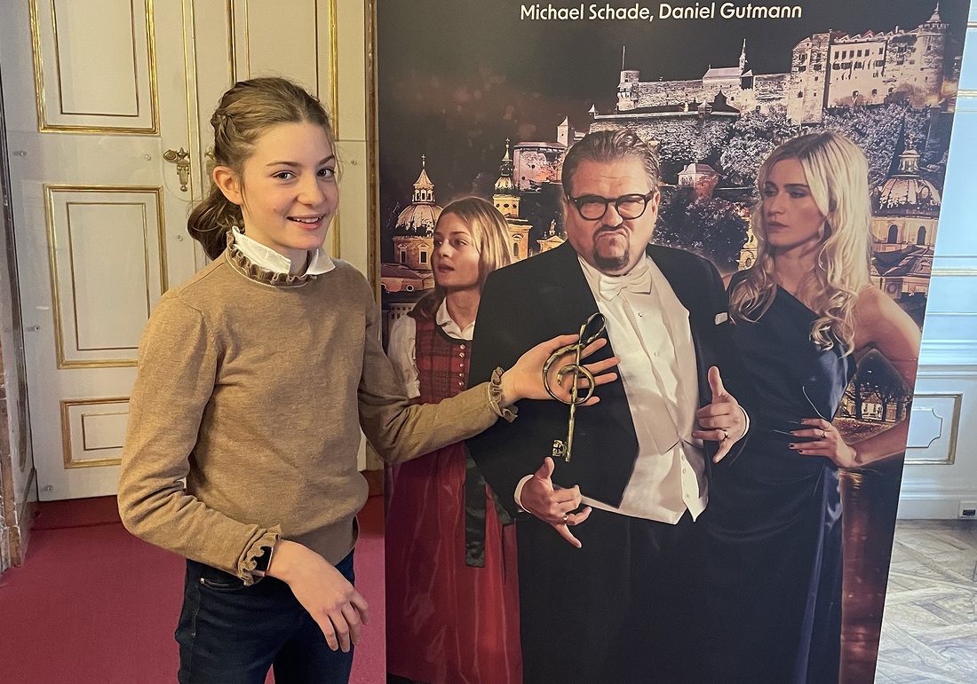 Leopoldine Richards (12) und ihr „magischer Schlüssel“ vor dem Filmplakat mit Tenor Michael Schade und Sopranistin Miriam Kutrowatz.  